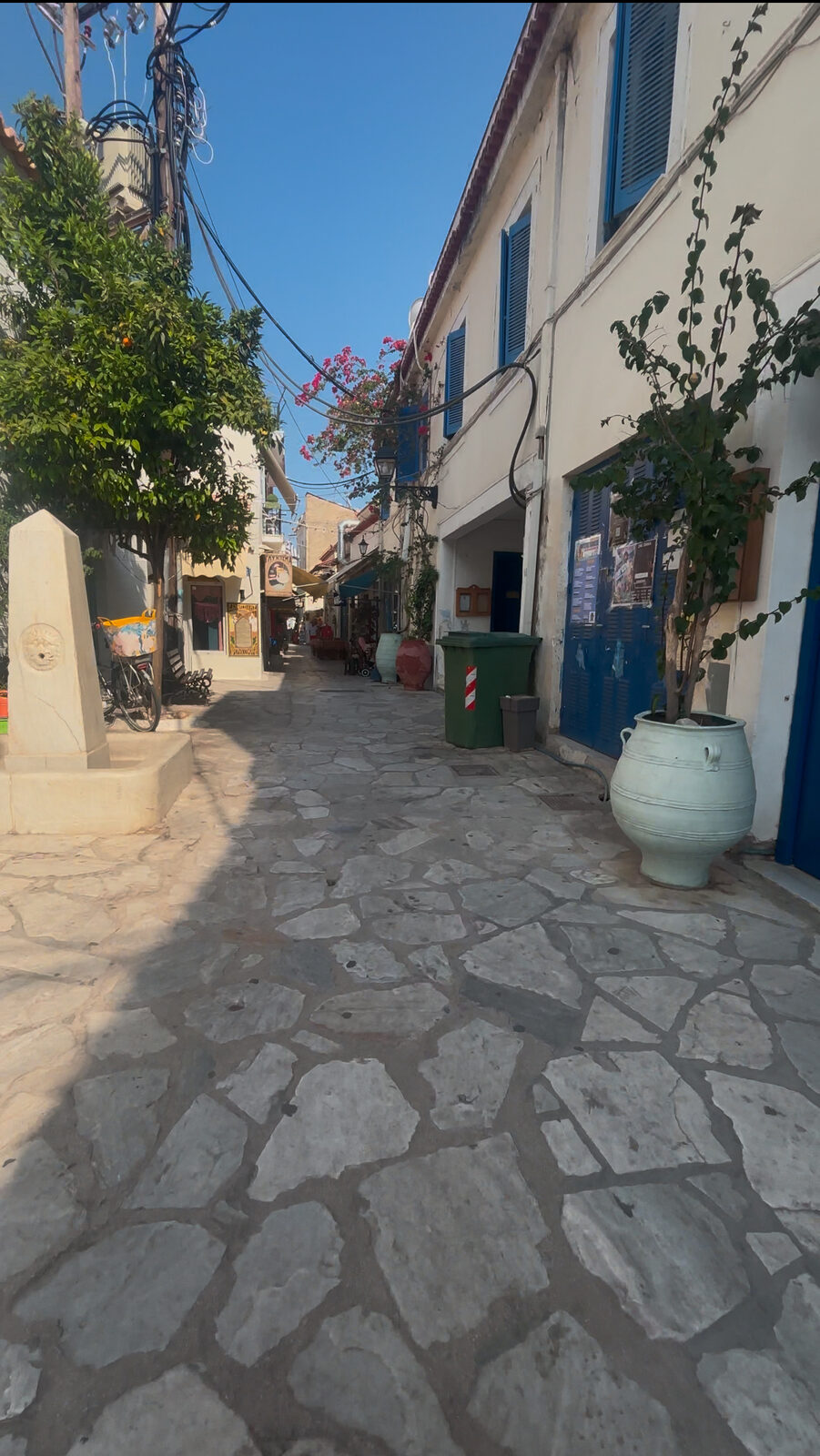 Whitewashed lane with blue shutters in dog-friendly Poros town, Greece